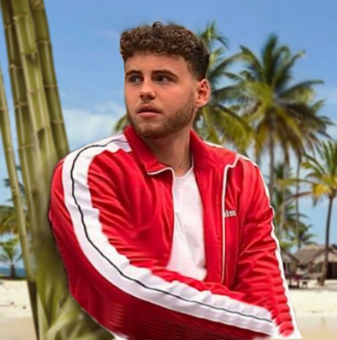 Arthur Allard, youtubeur musique, en veste rouge sous les palmiers